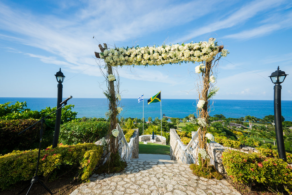 Flower-draped arch overlooking lush grounds, flags, and the sea at Tryall Club in Montego Bay, Jamaica